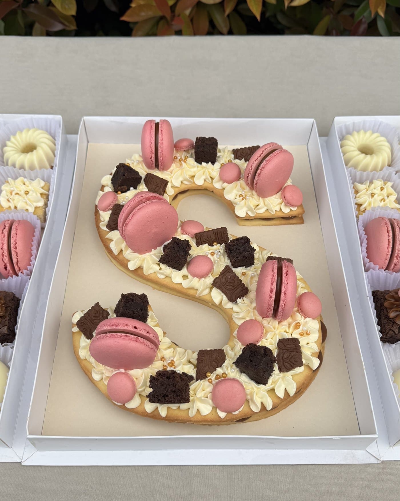 LetterCake con la letra S, decorada con macarons rosados y flores