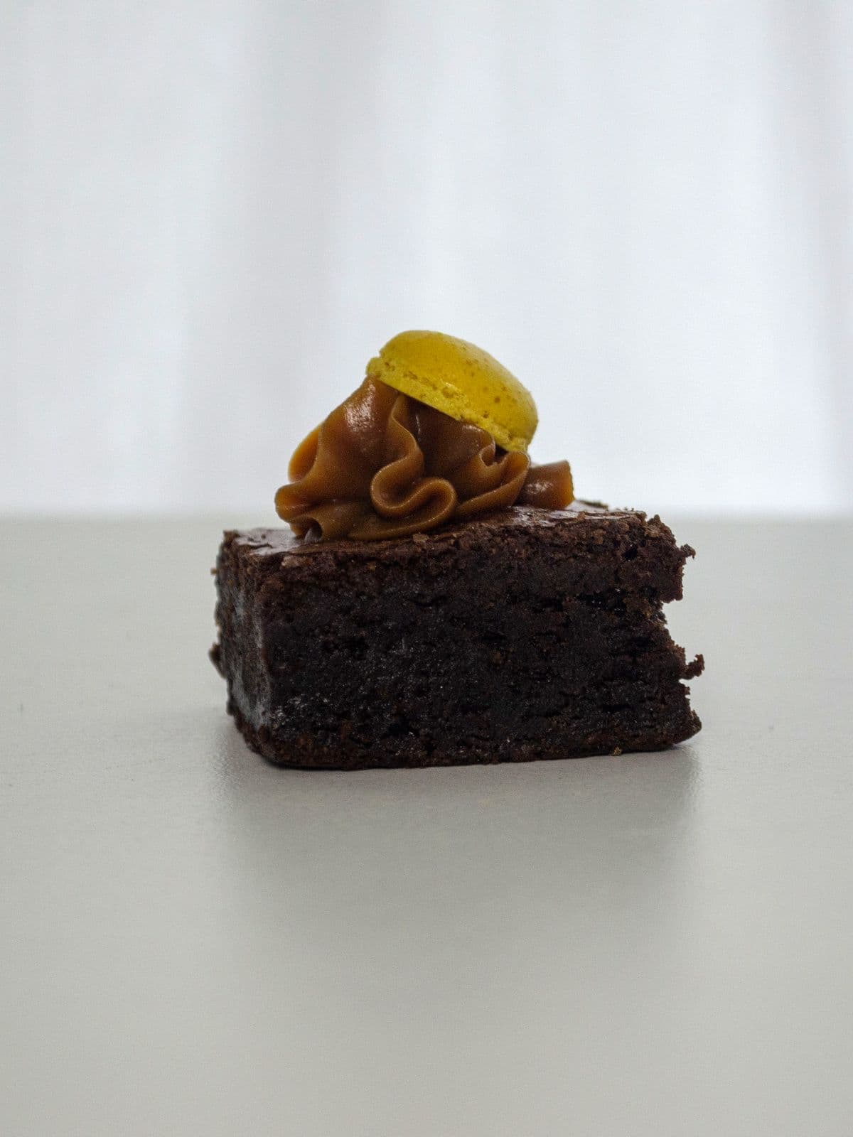Brownie húmedo con dulce de leche y media tapa de macaron amarillo