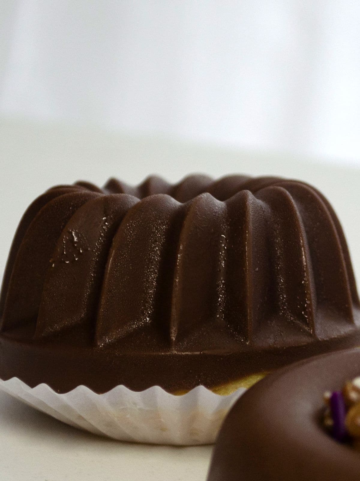 Budín individual bañado en chocolate, con la forma acanalada del molde