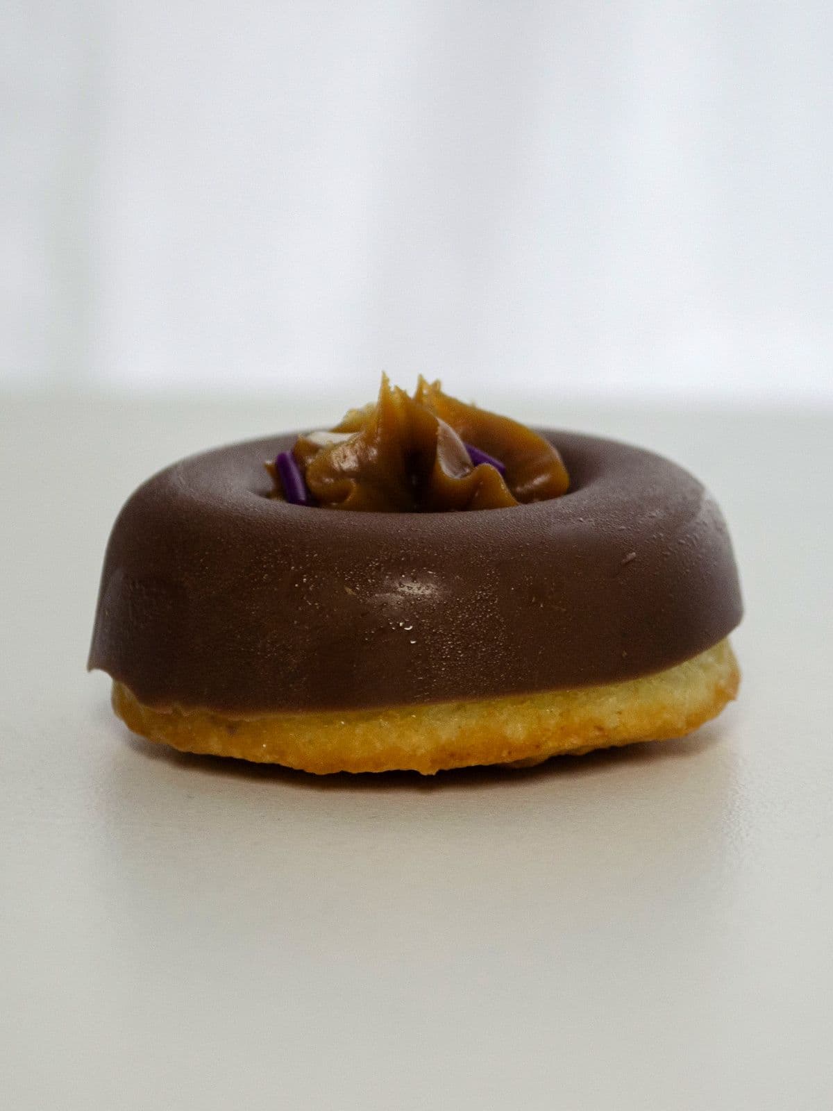 Donita bañada en chocolate con un copete de dulce de leche