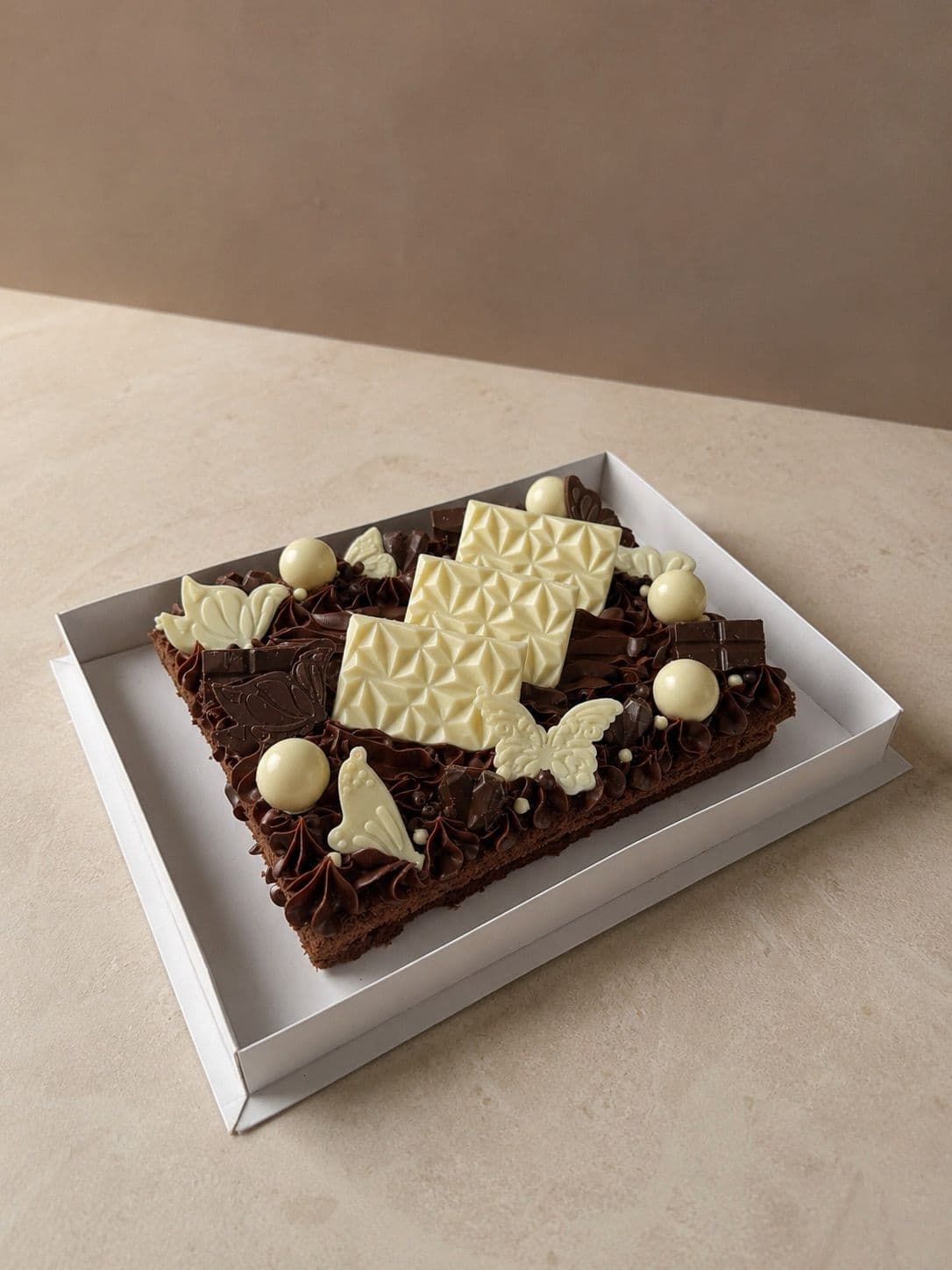 La Matilda en su caja sobre una mesa de mármol, con tres placas de chocolate blanco texturado al centro